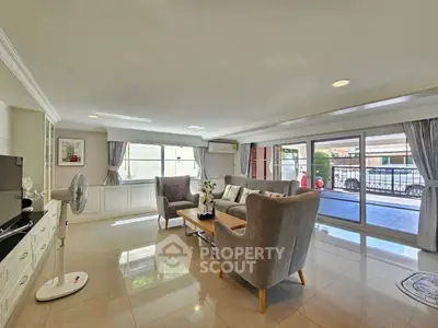 Spacious living room with elegant furniture and large windows offering natural light and balcony access.