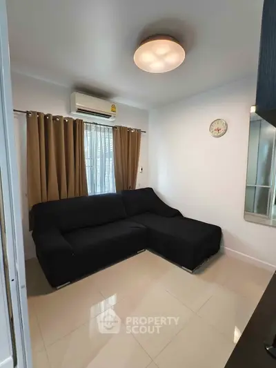 Cozy living room with modern black sofa and air conditioning, perfect for relaxation.