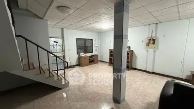 Spacious living room with staircase and tiled flooring in a cozy home.