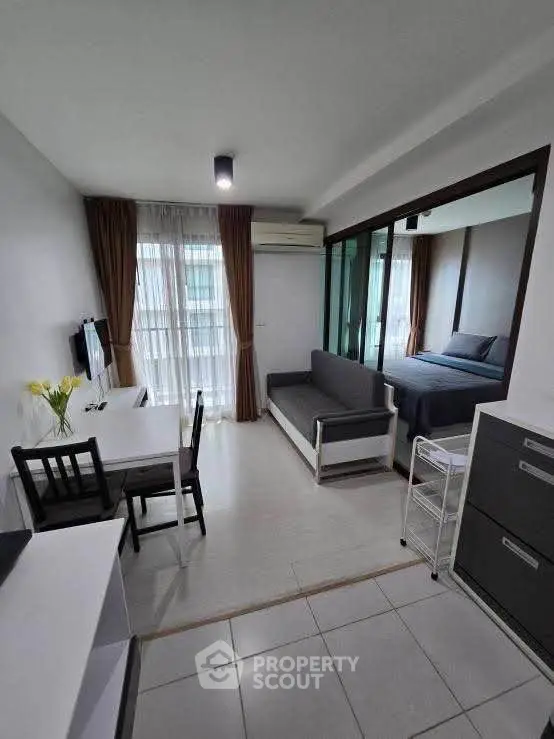 Modern studio apartment with open layout, featuring a cozy living area and bedroom separated by glass partition.