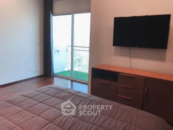 Modern bedroom with wall-mounted TV and balcony access