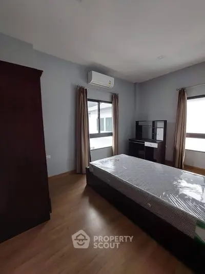 Spacious bedroom with large windows and modern furnishings in a well-lit apartment.