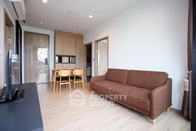 Modern living room with brown sofa and dining area in open layout apartment.