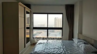 Modern bedroom with large window offering city view and stylish furnishings.