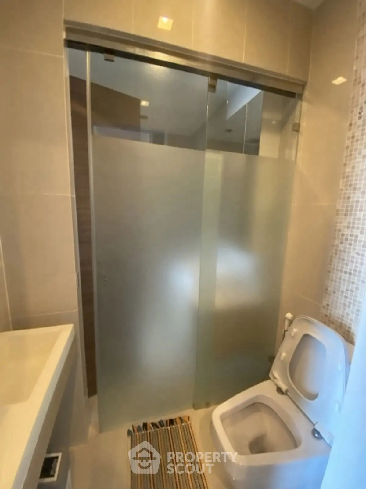 Modern bathroom with frosted glass shower and sleek toilet design.