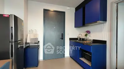 Modern kitchen with blue cabinets and sleek appliances in a stylish apartment.