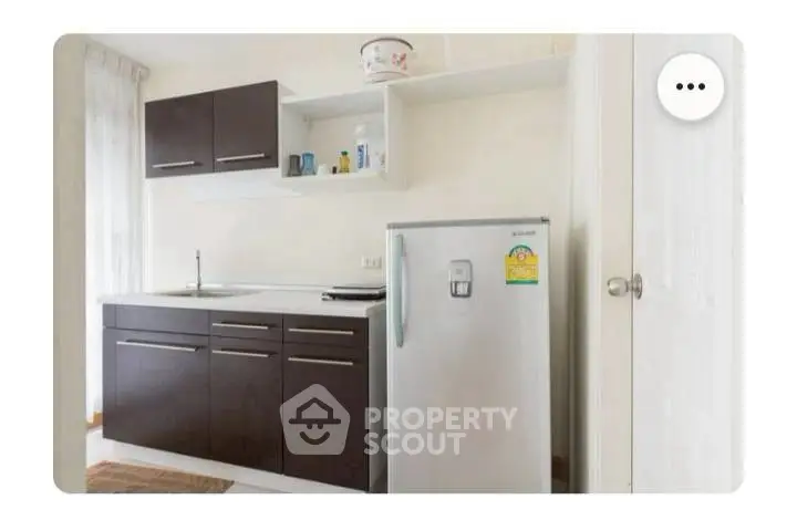 Modern kitchen with sleek cabinets and compact fridge in cozy apartment.