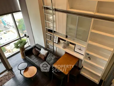 Modern loft-style living room with high ceilings and large windows offering city views.