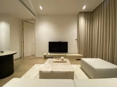 Modern living room with minimalist design, featuring a sleek TV setup and elegant furnishings.