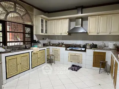 Spacious kitchen with classic cabinetry and modern stainless steel range hood.