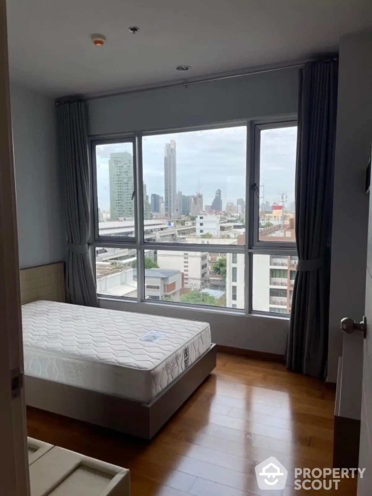 Modern bedroom with city view and large windows in high-rise apartment