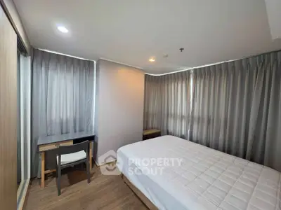 Modern bedroom with large windows and sleek furnishings in a stylish apartment.