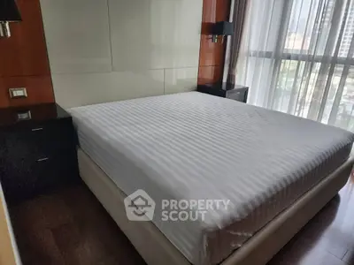 Spacious bedroom with large bed and city view window, perfect for relaxation.