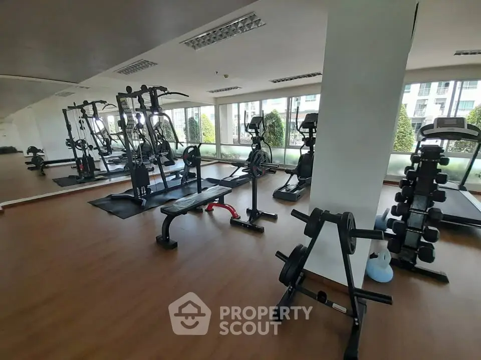 Spacious gym with modern equipment and large windows in a residential building.