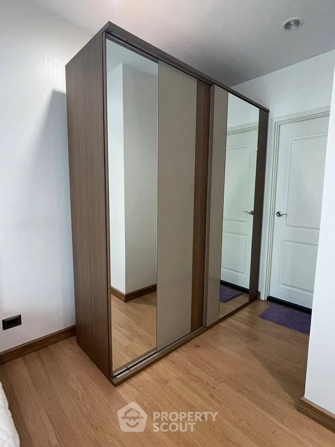 Modern bedroom with sleek mirrored wardrobe and wooden flooring