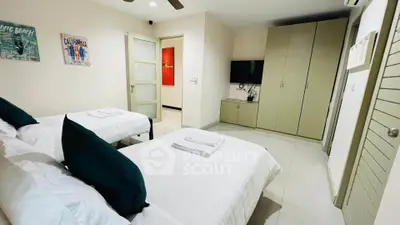 Spacious bedroom with twin beds, modern decor, and ample storage in a stylish apartment.