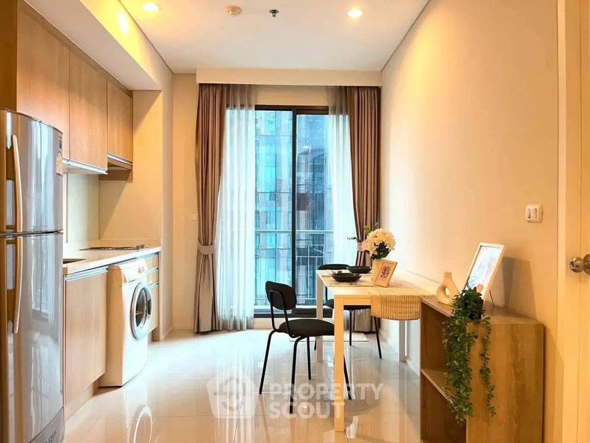 Modern apartment interior with kitchen and dining area, featuring sleek appliances and stylish decor.
