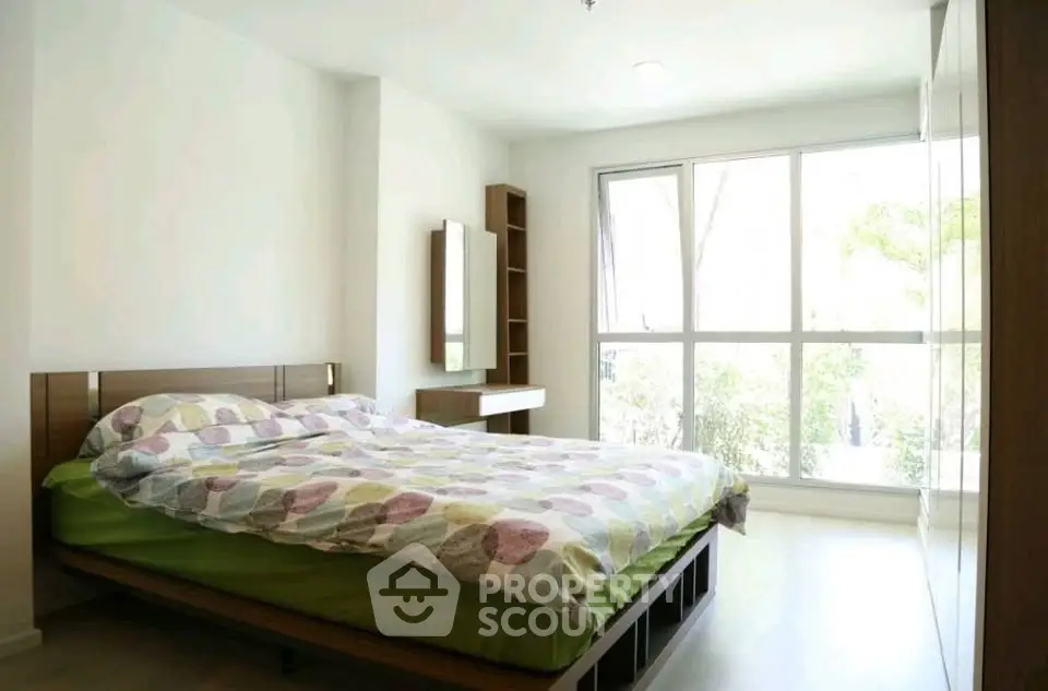 Bright and airy bedroom with large window and modern furnishings.