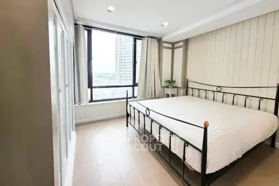 Bright and airy bedroom with large window and modern decor in urban apartment.