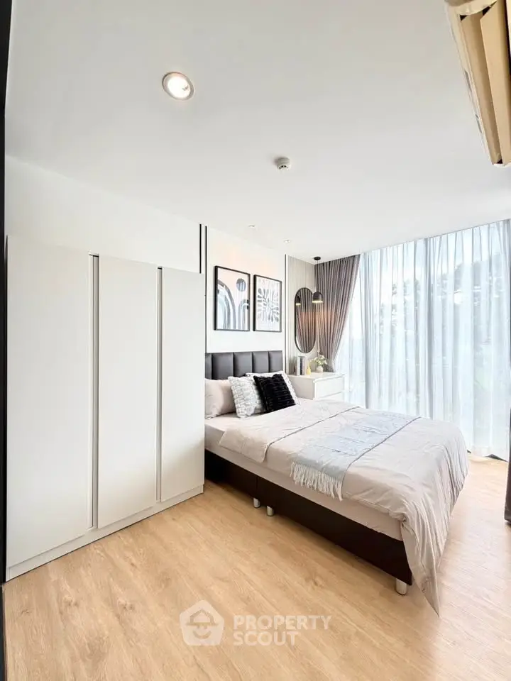 Modern bedroom with large windows, stylish decor, and natural light.