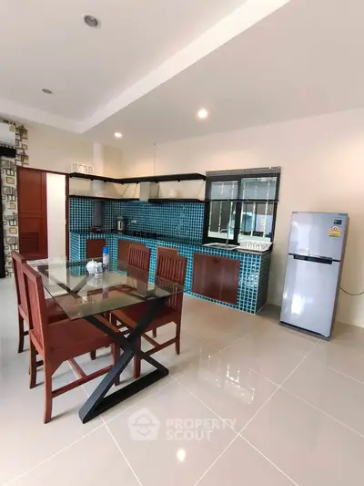 Modern kitchen with open layout and dining area, featuring sleek appliances and stylish decor.