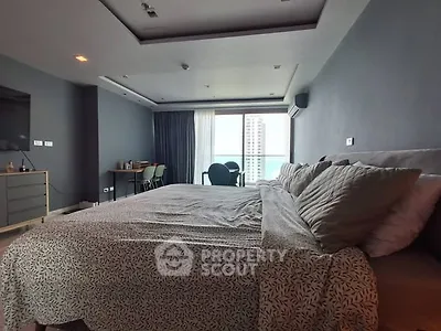 Spacious modern bedroom with large windows and city view, featuring stylish decor and comfortable bedding.