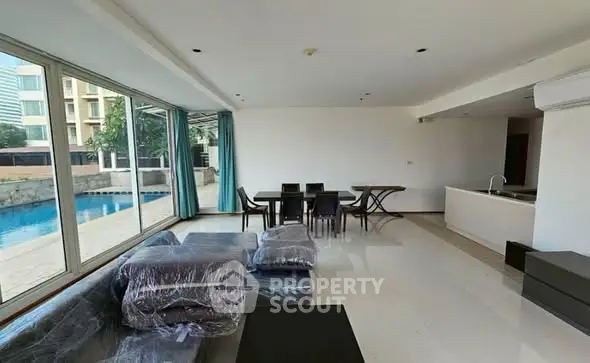 Spacious living room with pool view and modern furniture in luxury apartment.