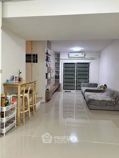 Spacious living room with modern furniture and sleek tile flooring, perfect for relaxation and entertainment.