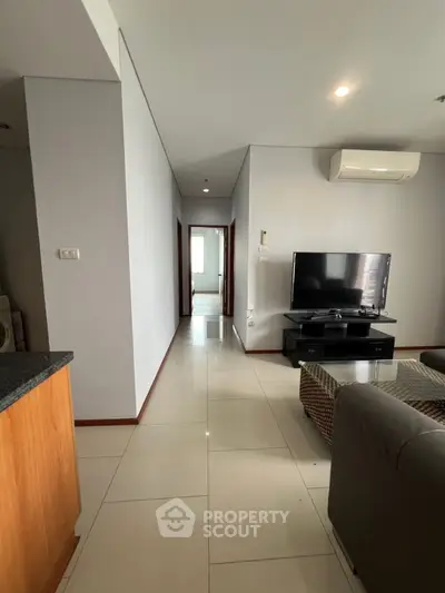 Spacious living room with modern TV setup and sleek air conditioning unit.