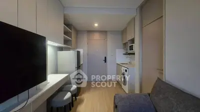 Modern apartment interior with sleek kitchen and cozy living area, featuring a washing machine and microwave.