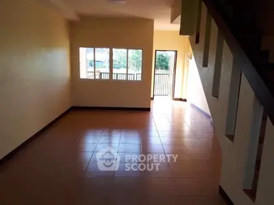 Spacious empty living room with staircase and natural light, ideal for customization.