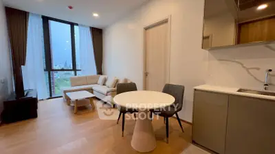 Modern living room with open kitchen, featuring stylish furniture and large windows with city view.