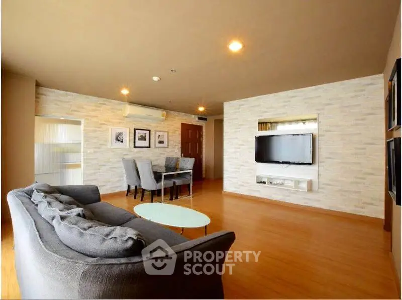 Spacious living room with modern decor and wall-mounted TV in a stylish apartment.