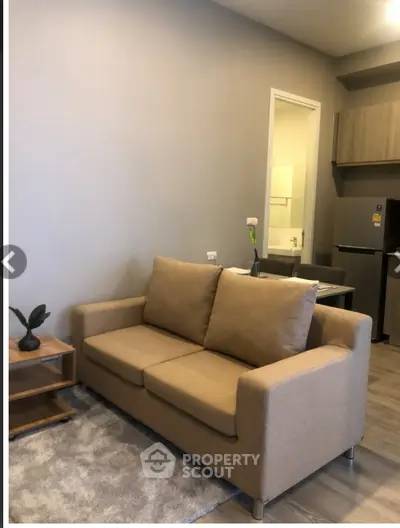 Cozy living room with beige sofa and modern kitchen area