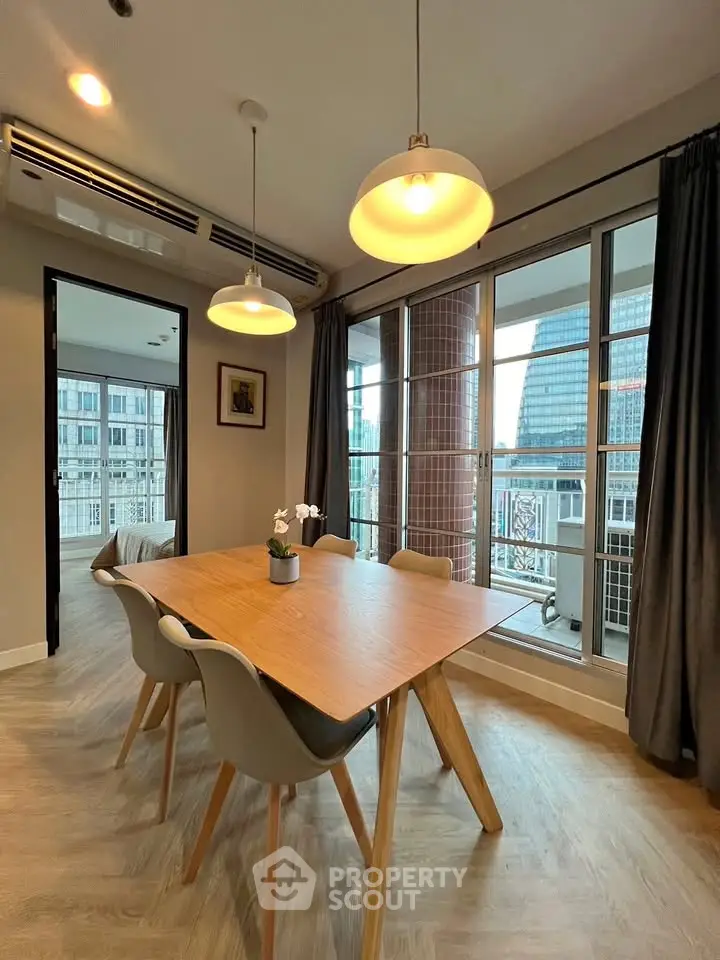 Modern dining area with stylish lighting and large windows offering city views.