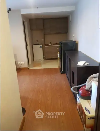 Compact kitchen with wooden flooring and modern appliances in cozy apartment.