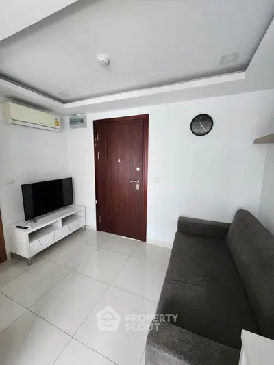 Modern living room with sleek furniture and wall-mounted TV in a cozy apartment.