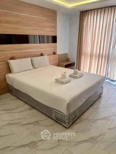Modern bedroom with stylish wood paneling and natural light from large windows.