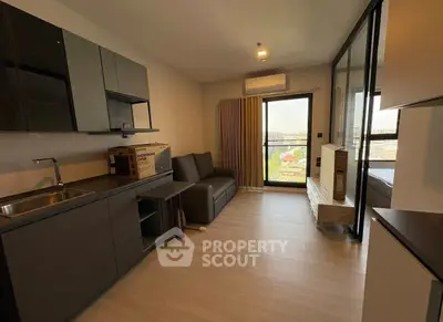 Modern apartment with open kitchen and cozy living area, featuring large windows and natural light.