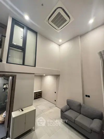Modern living room with high ceiling and cozy gray sofa, featuring sleek air conditioning unit.