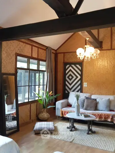 Charming living room with rustic wooden walls, cozy seating, and elegant chandelier, perfect for relaxation.