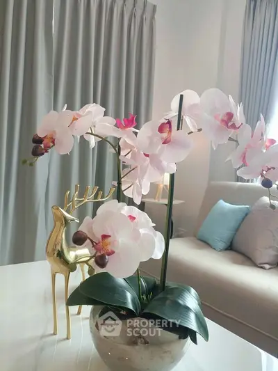 Elegant living room with stylish decor and plush seating, featuring a beautiful orchid centerpiece.