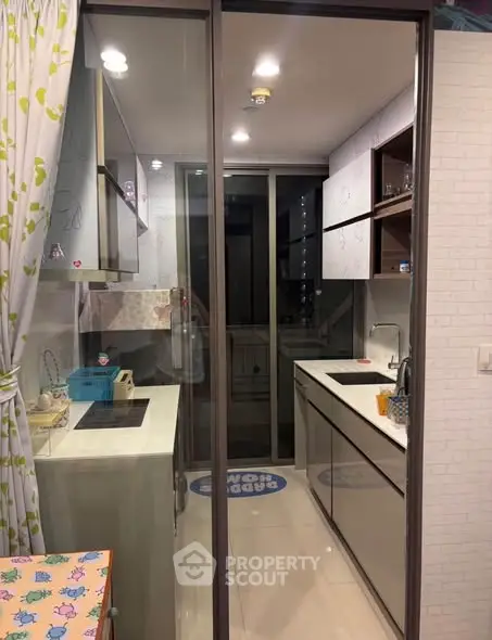 Modern kitchen with sleek cabinetry and glass partition in a compact layout.