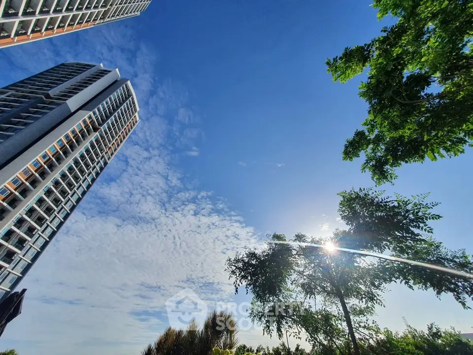 Stunning high-rise building with clear blue sky and lush greenery, perfect for urban living.
