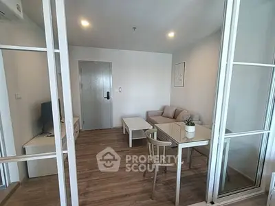 Modern living room with glass doors, cozy seating, and wooden flooring.