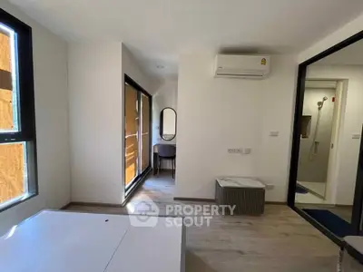 Modern apartment interior with air conditioning and stylish decor, featuring a compact workspace and large windows.