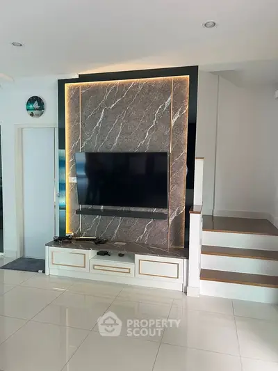 Modern living room with sleek TV setup and elegant marble accent wall.