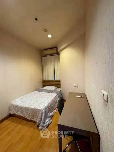 Cozy small bedroom with wooden flooring and minimalist furniture, perfect for a compact living space.