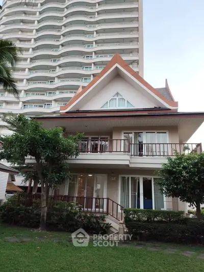 Charming two-story house with lush garden and modern high-rise backdrop, perfect blend of traditional and contemporary living.