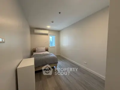 Minimalist bedroom with modern flooring and air conditioning, perfect for a cozy living space.